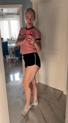 Woman takes mirror selfie while child cleans in background