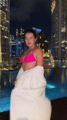 Woman at Jakarta rooftop pool, pink lilies captured nighttime