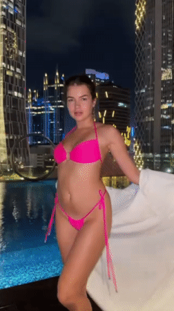 Woman at Jakarta rooftop pool, pink lilies captured nighttime