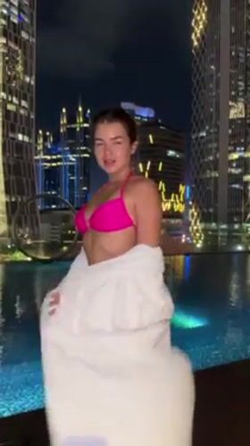 Woman at Jakarta rooftop pool, pink lilies captured nighttime