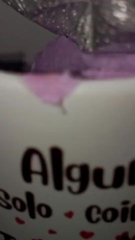 The video shows a mug with the message "Algunos solo coinciden yo te amo" (Some just match, I love you) along with cartoon images of Stitch and Angel from the Disney movie Lilo & Stitch. Behind the mug are plush toys resembling Stitch and Angel, along with a gift wrapped in silver cellophane. The camera focuses on the mug and then pans slightly to show the plush toys and the gift.