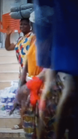 Red-gloved figure in vibrant outfit outside Barden Yana building