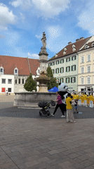 Yellow-shirted group gathers near fountain with panda costume in Bratislava