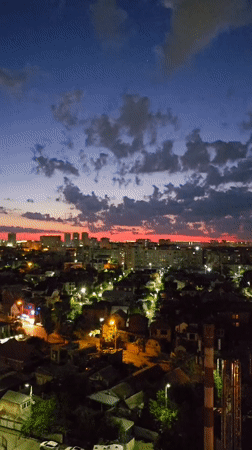 Krasnodar skyline at dusk with crescent moon and vivid sunset.