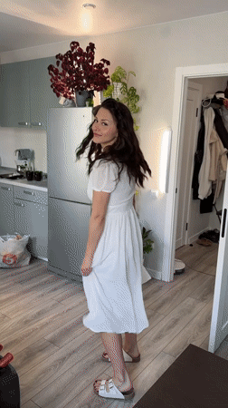 Woman in white dress moves through home kitchen in Murino