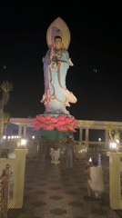 Visitors photograph illuminated religious statue in Vietnam courtyard