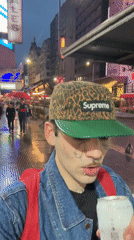 Young man drinks on wet Buenos Aires street at dusk