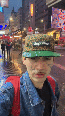 Young man drinks on wet Buenos Aires street at dusk