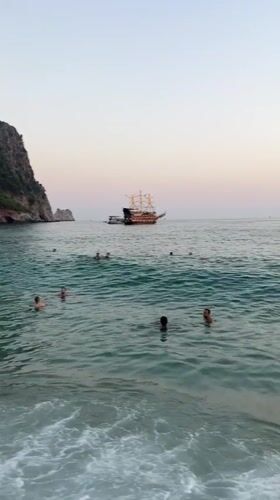 Swimmers, waves, and a tall ship off the Alanya coast