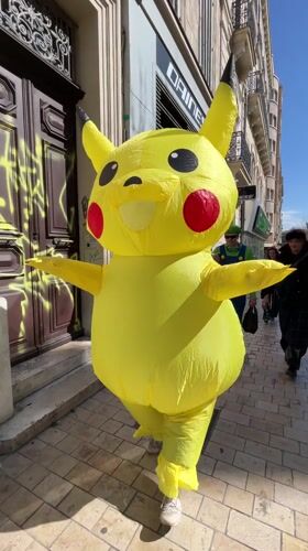 Person in inflatable Pikachu costume walks Marseille sidewalk