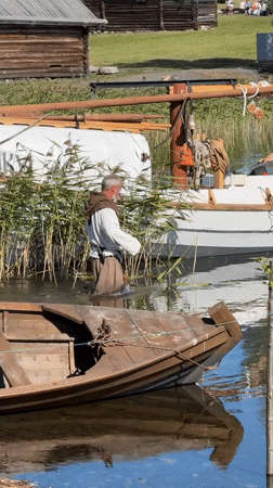 Historical waterfront scene with period boats and traditional architecture