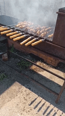 Outdoor grill spread with skewers and veg near a Russian-marked venue