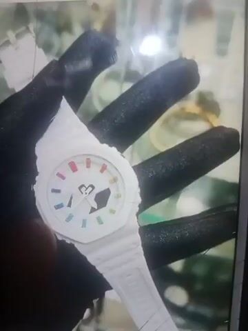 This video is a screen recording of a phone displaying multiple images. The dominant image on the left is a close-up of a black G-Shock watch. Several other images are visible on the right side of the screen, including more G-Shock watches, some in their boxes, and possibly other accessories. The recording appears to be taken from a distance, and the phone screen is slightly tilted. There is some light glare on the screen. The video begins with a black screen and then transitions to the phone display. A finger is visible in the bottom left corner of the screen in the first few seconds of the video.