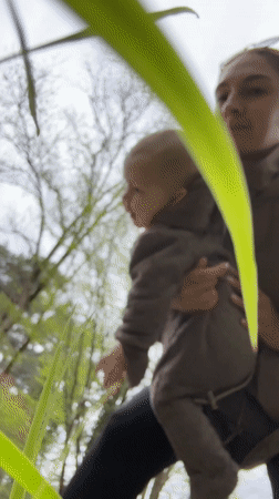 Woman holds baby outdoors in Sochi park area