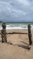 Overcast tropical beach with debris, rough surf, and weathered rope posts