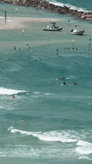 Netanya beach buzzes with swimmers, seen from above and cliff