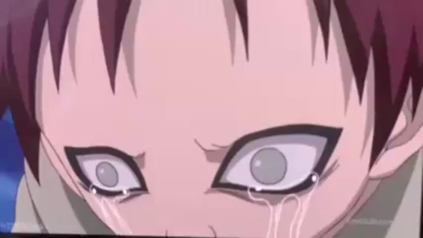 The video displays a close-up image of a character with maroon hair, pale skin, and large, grey eyes filled with tears. The character's brow is slightly furrowed, indicating distress or sadness. The background is a blur of muted colors. The image appears to be a still from an animation.