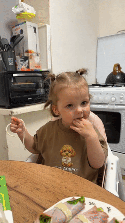 Toddler enjoys mealtime with family in Russian home kitchen