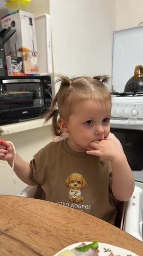 Toddler enjoys mealtime with family in Russian home kitchen
