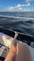 Person relaxes on sailboat in sunny Chaykovsky waters