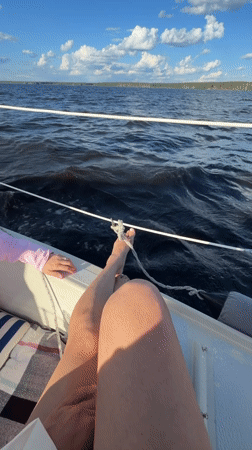 Person relaxes on sailboat in sunny Chaykovsky waters