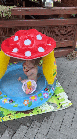 Toddler plays in mushroom-shaped inflatable pool with toys