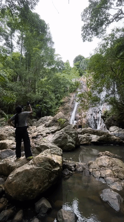 Tourists photograph tropical waterfall in Ko Samui jungle setting