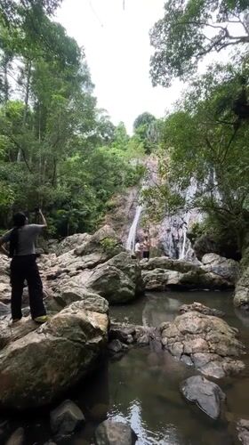 Tourists photograph tropical waterfall in Ko Samui jungle setting