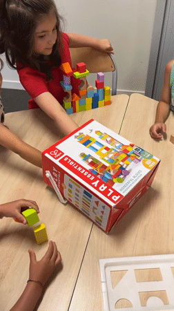 Kids build block towers and do coloring at a table in La Fouillouse
