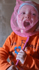 Child plays with pink net, laughs during playtime