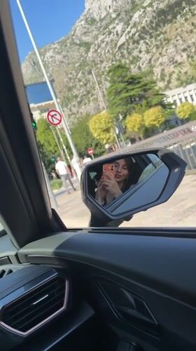 Woman takes selfie with orange phone while driving in Montenegro