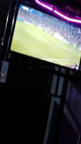 A large TV screen displays a soccer match, likely in a dark room illuminated by pink LED strip lights along the ceiling. The score on the screen indicates "PSG 5 0 INT" and the game time is around 87:45-87:51. Players in yellow, green, and blue jerseys are visible on the field. At one point, a player identified as "24 MAYULU" with "2 GOALS IN 4 MATCHES" is shown up close. Another shot briefly features a coach, who appears to be Jose Mourinho, looking contemplative. A person in a red shirt, with text "Squad", "ERTY", and "oth" partially visible, is seen in the foreground watching the game intently. The setting appears to be an indoor entertainment area, possibly a bar or a home theater, in Ruaka, Kenya, given the low light and vibrant lighting.