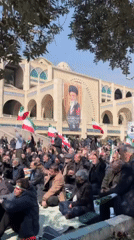 Crowd gathers at Tehran building displaying religious portrait