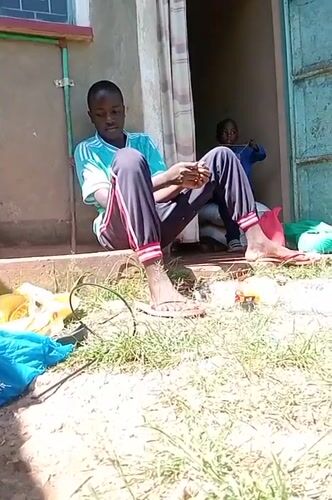 Young man in Kenya observed doing yard work, crafting
