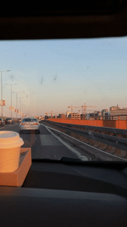 Driver crosses orange-railed bridge in Belgrade under blue skies