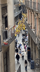 Yellow-shirted demonstrators march through narrow Barcelona street