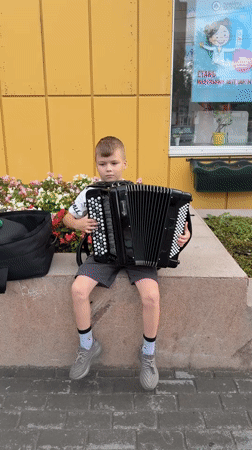 Street musicians perform outside a yellow building in Surgut