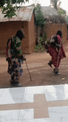 Traditional masked performers dance in Nigerian village courtyard