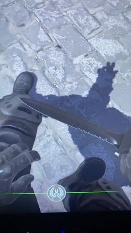 The video shows a first-person view of a Counter-Strike: Global Offensive (CS:GO) game. The player is holding a serrated knife in their hands. The player is standing on a cobblestone surface. Another player walks by. The environment appears to be a Middle Eastern-themed map with blue and white buildings. A sign in Arabic is visible on one of the buildings. The player's username, "zylx KEBAAAAB," is displayed along with their cash amount, $0.