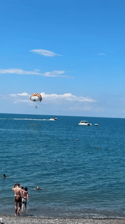 Sochi beach day: parasailing, boats, and swimmers on the shore