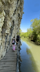 Tourists traverse wooden cliffside walkway in Petrevene, Bulgaria