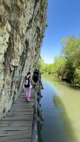 Tourists traverse wooden cliffside walkway in Petrevene, Bulgaria