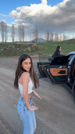 Young people gather around BMW on rural road in Armenia