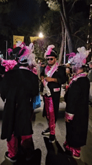 Costumed performers gather as police manage nighttime street scene
