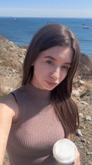 Woman enjoys morning coffee on rocky coastal cliff