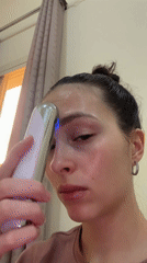 Woman uses blue light facial device in Abu Dhabi