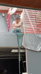 Woman washes plastic sheet with hose in Thailand