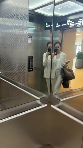 Woman takes elevator selfie with luxury shopping bag in Dubai