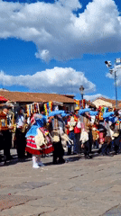 Costumed dancers perform rainbow parade routine on stone pavement