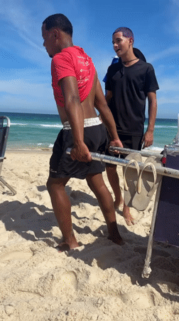 Two men spotted walking on Rio beach during sunny afternoon